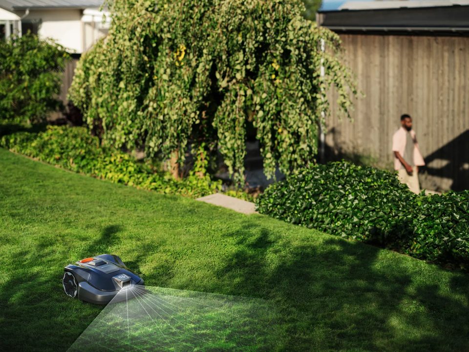 The Aspire R6V mowing a back lawn while a man walks through the garden